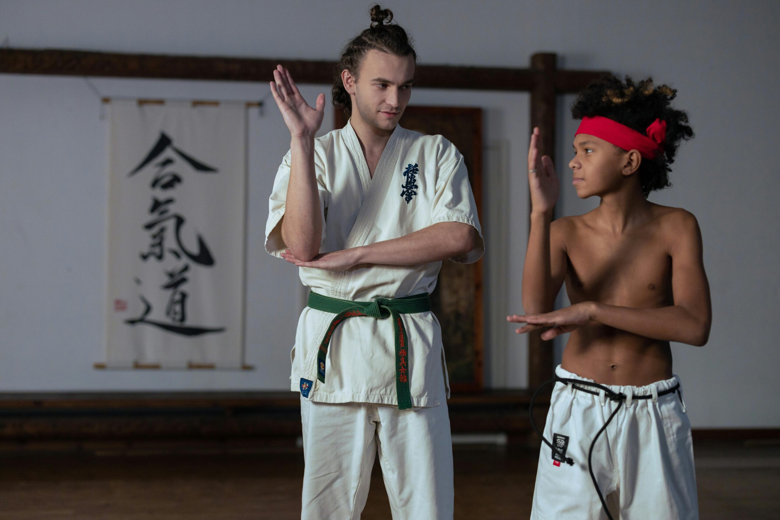 Instructor teaching karate to a young boy in a dojo setting.